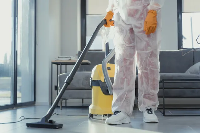 Specialist în echipament de protecție aspirând podeaua unui living modern